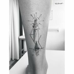 a black and white photo of a lighthouse tattoo on the leg