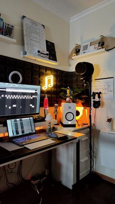 a computer desk topped with a laptop computer and monitor next to a sound board on top of a hard wood floor