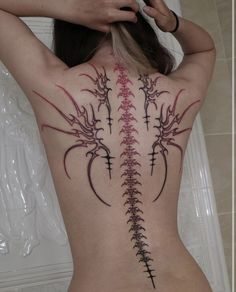 the back of a woman's body with an intricate tattoo design on her ribs