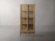 a tall wooden bookcase with glass doors on the front and bottom shelves, in an empty room