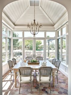 a dining room table with chairs and a chandelier hanging from it's ceiling