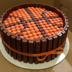 a chocolate cake with orange and black candies in the shape of squares on top