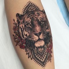 a black and white tiger tattoo on the left arm, with flowers around its neck