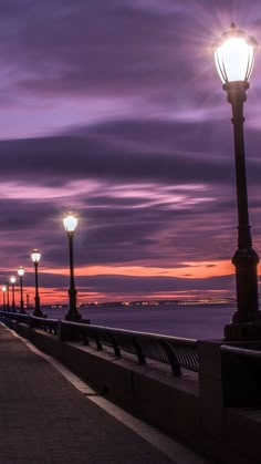 a street light sitting next to the ocean under a purple sky