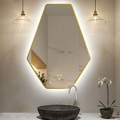 a bathroom sink with a mirror above it and lights hanging from the wall behind it