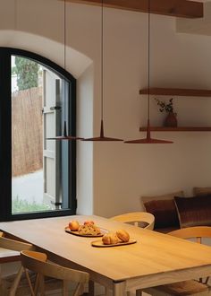 a wooden table sitting in front of a window next to a wall mounted light fixture