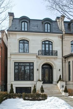 a large white house with lots of windows and snow on the ground in front of it