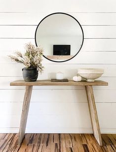 a wooden table topped with a mirror and vase filled with flowers