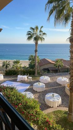 an outdoor dining area overlooking the ocean with tables and chairs set up for a formal function