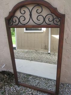 a mirror sitting on top of a gravel covered ground next to a building with a window