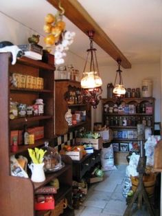 the inside of a store with lots of items on shelves and lights hanging from the ceiling