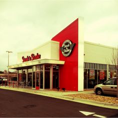 an empty street in front of a store with cars parked on the side of it