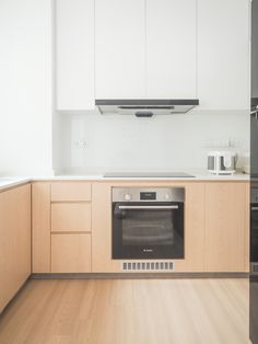 an empty kitchen with wood floors and white cabinets, including a stove top oven in the center