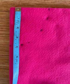 a pink piece of cloth with a measuring tape on it and some holes in the fabric