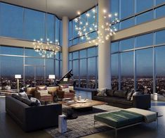 a living room filled with lots of furniture and large windows overlooking the city at night