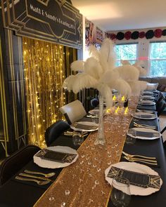 a long table set with black and gold place settings, white plates and silverware