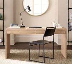 a desk with a chair and a round mirror on the wall in front of it