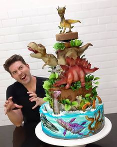 a man standing in front of a cake with dinosaurs on it