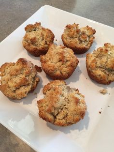 several muffins on a white plate sitting on a table