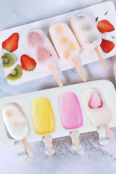 four popsicles with fruit on them sitting on a plate