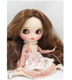 a doll with long brown hair wearing a pink dress