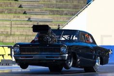 an old car driving down a race track with the hood up on it's engine