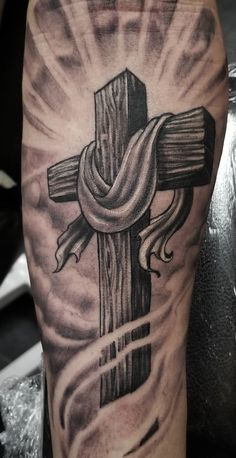 a cross with flames coming out of it on someones leg in black and grey