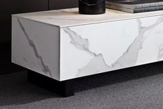 a white marble sideboard with black legs on carpeted flooring next to books