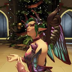 a woman dressed up as a fairy with wings and green hair sitting in front of a christmas tree