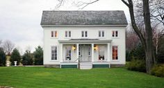 a white two story house sitting on top of a lush green field