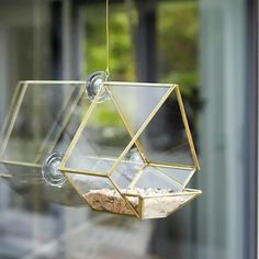 a bird feeder hanging from the side of a glass window with gravel in it's bottom