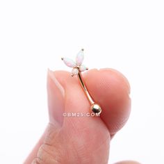 a tiny dragon shaped nose ring in gold with white opals on it's back