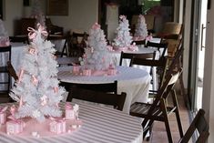 there are many white trees with pink bows on the table and in front of them