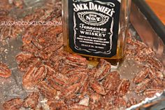 a bottle of jack daniels whiskey sitting on top of some pecans in a pan