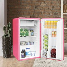 an open pink refrigerator sitting in front of a brick wall