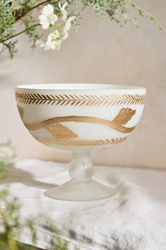 a white bowl sitting on top of a table next to a vase with flowers in it