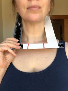 a woman holding a ruler in front of her face with one piece missing from it