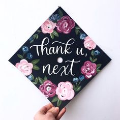 a hand holding up a graduation cap with flowers on it that says, thank u next