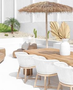 a wooden table with white chairs and an umbrella