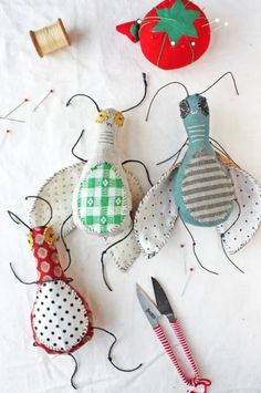 three fabric ornaments are sitting on a table with scissors, thread and spools