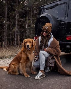 a woman sitting on the ground next to two dogs