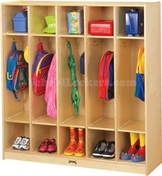 a child's wooden locker with many coats and shoes