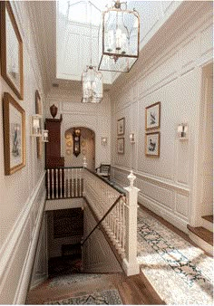 the stairs in this house are white and have chandeliers hanging from it's ceiling