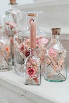 some glass bottles with flowers in them and a candle