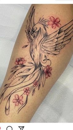 a woman's leg with a bird and flowers tattoo design on the side of her thigh