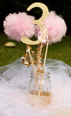 two pink and gold cake toppers in a mason jar with tulle on the table