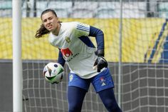 a female soccer player in action on the field with her ball and gloved hands