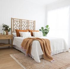 a bedroom with white walls and wood floors has a large bed covered in tan blankets