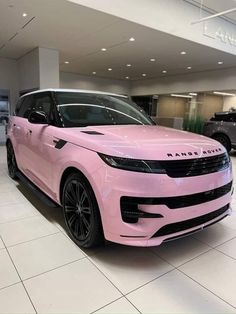 a pink range rover parked in a showroom