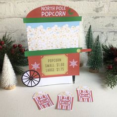 a popcorn cart with three small christmas trees next to it